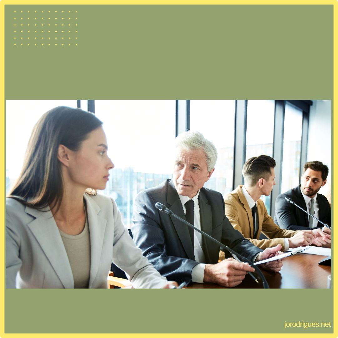 A young woman and older man looking at each other at a board meeting. Potentially upset with each other.